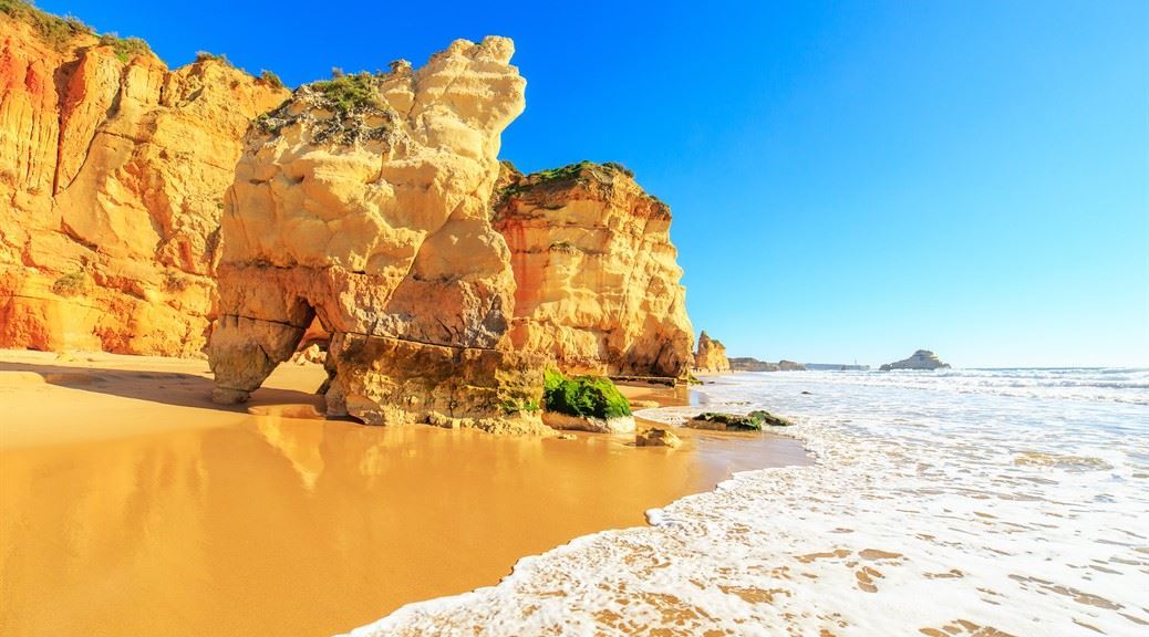 Golden rock formation on sea shore at praia da rocha portugal